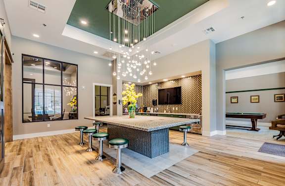 A modern kitchen with a bar area and a pool table.