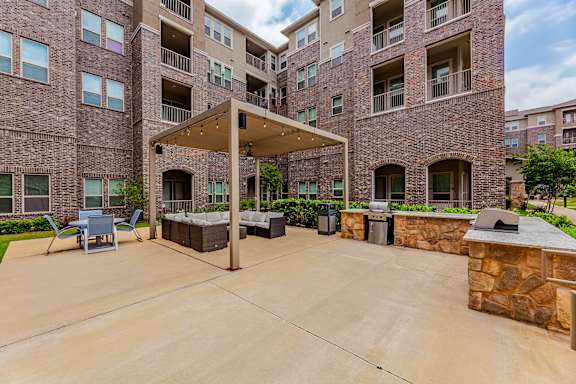 A large outdoor patio area with a stone wall and a pergola.