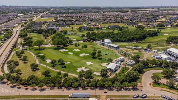 A golf course is surrounded by apartment buildings.