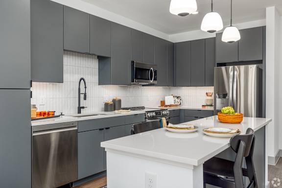 A modern kitchen with a white island and grey cabinets.