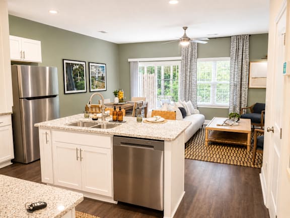 A kitchen with a refrigerator, sink, and a dining table with chairs.