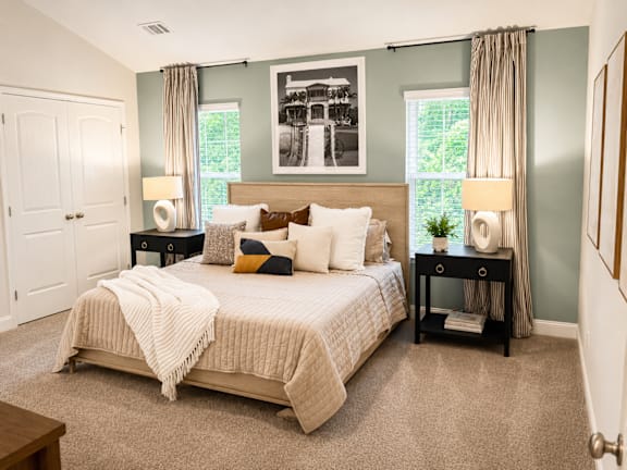 A bedroom with a large bed and a painting on the wall.