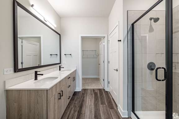 A bathroom with a sink, mirror, and shower.