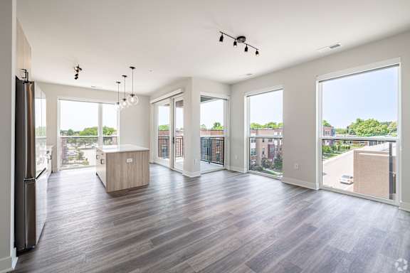 A spacious kitchen with wood flooring and a refrigerator.
