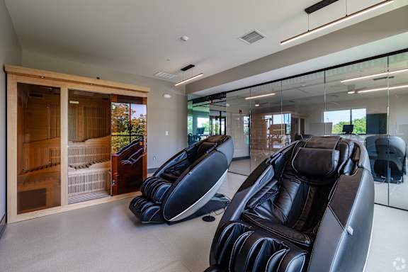 A modern living room with black leather chairs and a glass wall.