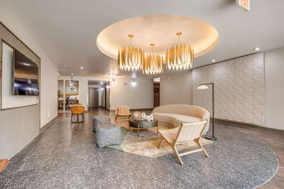 A modern living room with a large circular light fixture and a grey carpet.