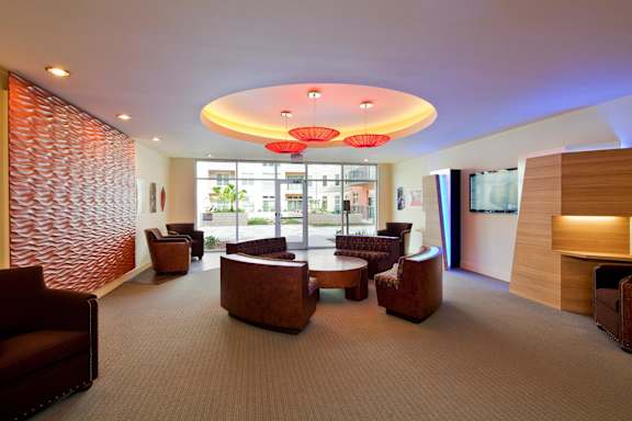 A modern lounge area with brown leather chairs and a carpeted floor.