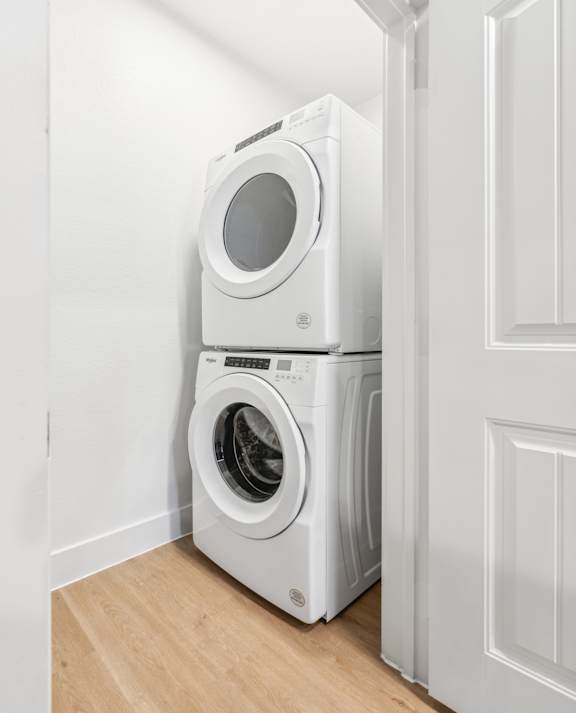 A white washing machine and dryer stacked on top of each other in a laundry room.