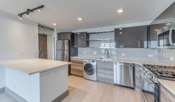 A modern kitchen with stainless steel appliances and a wooden floor.