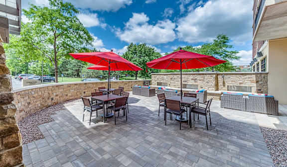 A patio with a table and chairs under red umbrellas.
