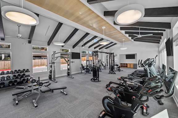 A gym with a variety of equipment including treadmills, weights, and exercise machines.