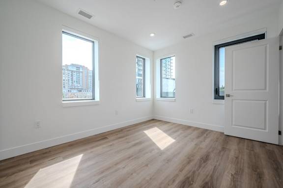 an empty living room with a door and three windows