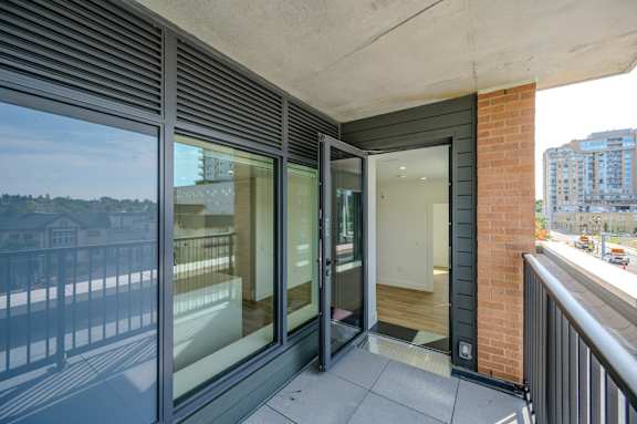 a balcony with a view of a city and a glass door