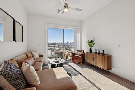 A living room with a brown couch and a ceiling fan. at Lura Vegas Apartments, Nevada