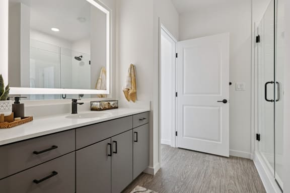 A bathroom with a white door and a mirror above the sink. at Lura Vegas Apartments, Las Vegas