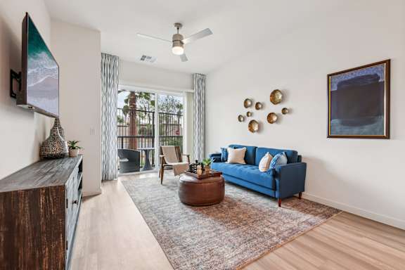 A living room with a blue couch and a flat screen TV mounted on the wall.at Coya Apartments, Las Vegas