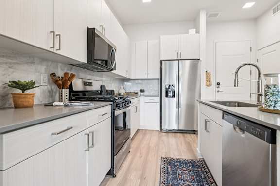 A modern kitchen with white cabinets and stainless steel appliances.at Coya Apartments, Las Vegas, NV, 89102