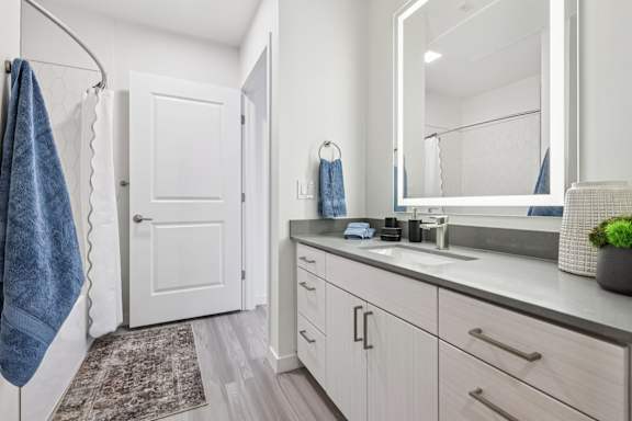 A bathroom with a white door, a mirror, and a sink.at Coya Apartments, Nevada