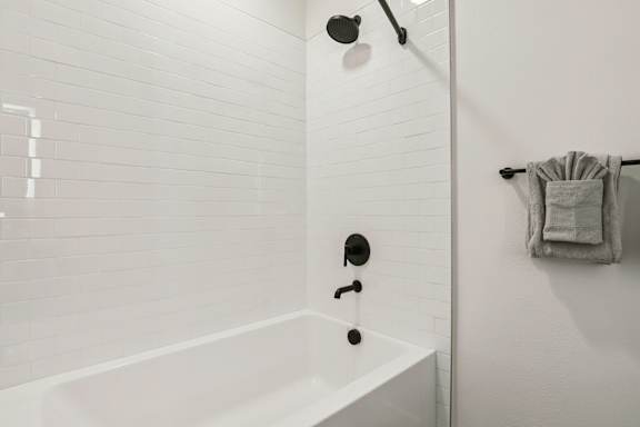 A white bathroom with a white tub and white tiles. at Lura Vegas Apartments, Las Vegas