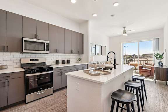 A modern kitchen with a white island and stainless steel appliances. at Lura Vegas Apartments, Las Vegas, NV