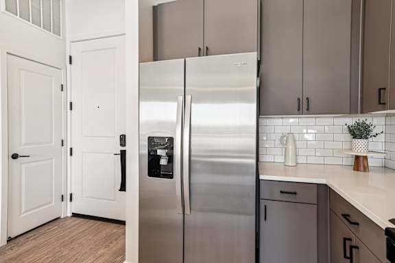 A stainless steel refrigerator in a kitchen with white cabinets. at Lura Vegas Apartments, Las Vegas, 89103