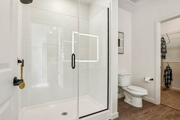 A white bathroom with a toilet and a walk in shower. at Lura Vegas Apartments, Nevada