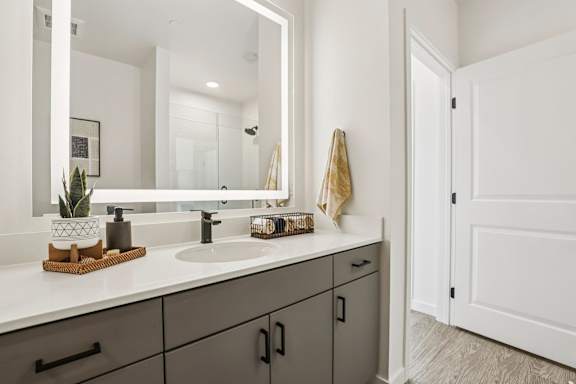 A bathroom with a white sink and grey cabinets. at Lura Vegas Apartments, Las Vegas