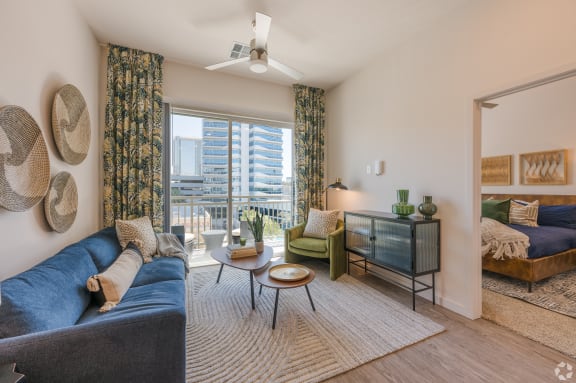 a living room with a blue couch and a large window at Aura Vegas Apartments, Nevada, 89103