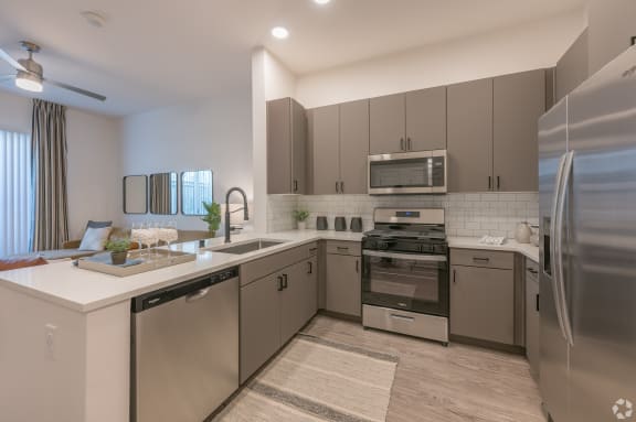 an open kitchen with stainless steel appliances and white counter tops at Aura Vegas Apartments, Nevada
