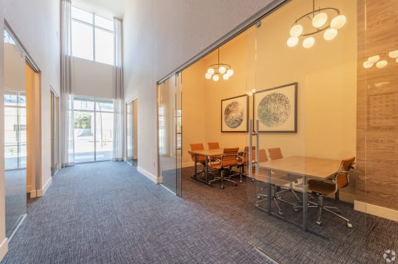 a conference room with a table and chairs and a glass wall at Aura Vegas Apartments, Las Vegas, NV 89103