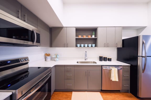 a kitchen with gray cabinets and white countertops at Hana Apartments, Hillsboro