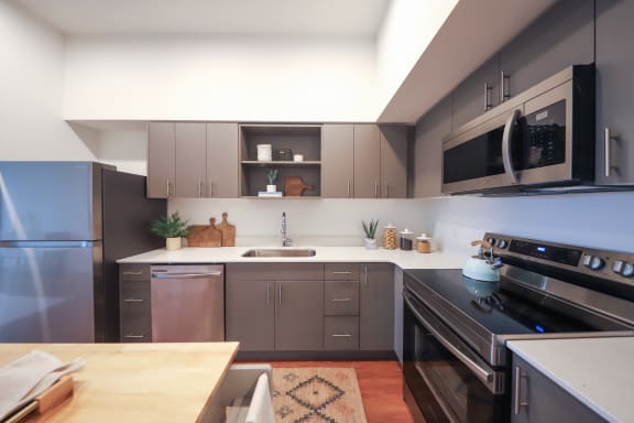a kitchen with gray cabinets and a wooden table at Hana Apartments, Hillsboro, Oregon