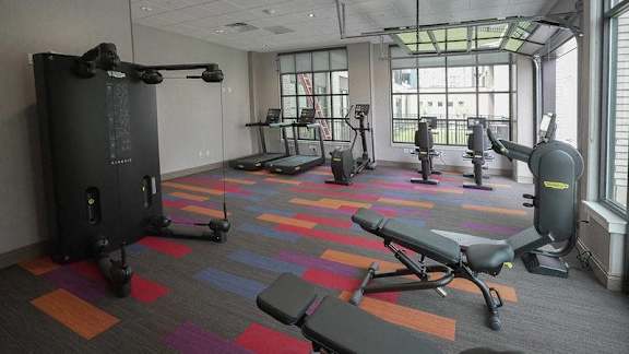A gym with a variety of equipment including treadmills, weights, and a bench at Denver Metro Village Apartments, Denver, 80204