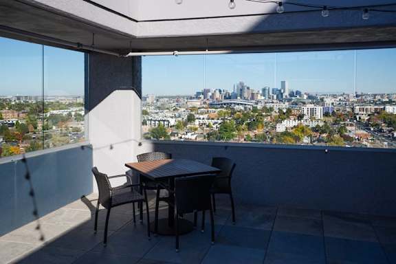 A table and chairs are set up on a patio overlooking a city at Denver Metro Village Apartments, Denver, Colorado
