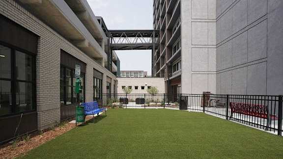 A small grassy area with a bench in the middle of a courtyard surrounded by buildings at Denver Metro Village Apartments, Denver, Colorado