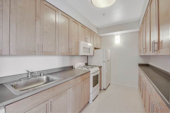 A kitchen with wooden cabinets and a white refrigerator. at Acton Courtyard, Berkeley, 94703