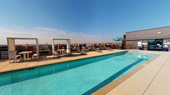 A large outdoor swimming pool with sun loungers and a building in the background.