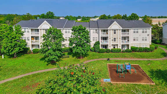 Playground area with apartment buildings and landscaping at Acclaim at Ashburn Apartments, Ashburn