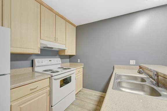 A kitchen with a white stove and sink at Oak Village Apartments, Oakland