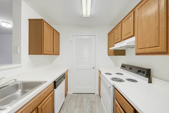 Galley kitchen with wood cabinets and white appliances at Acclaim at Ashburn Apartments, Ashburn