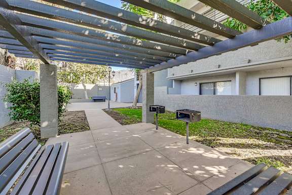 A concrete walkway leads to a mailbox under a metal pergola.