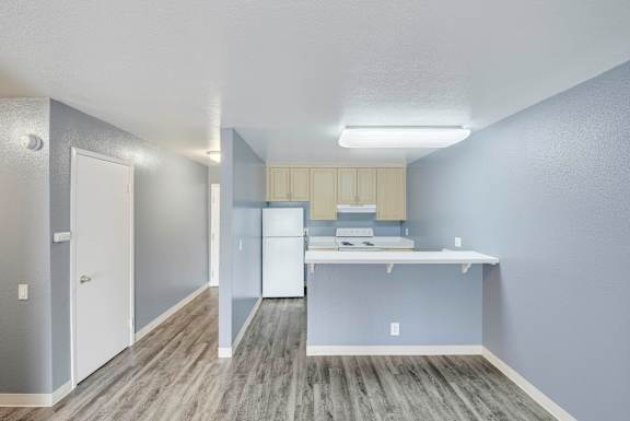 A kitchen with a white fridge and a white counter top at Oak Village Apartments, Oakland, CA