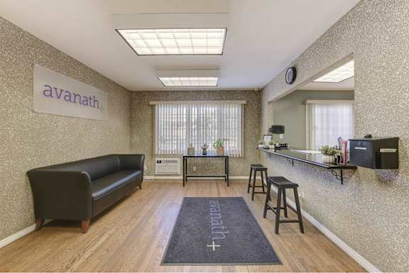 A well-lit office space with a black sofa and a wooden floor at Acclaim at Baldwin Apartments, California