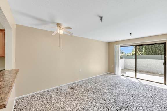 A room with a ceiling fan and carpeted floor.