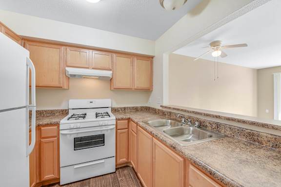 A kitchen with a white refrigerator, a white stove, and a granite countertop.