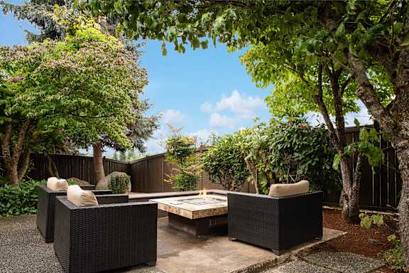 A patio with a table and chairs surrounded by trees.