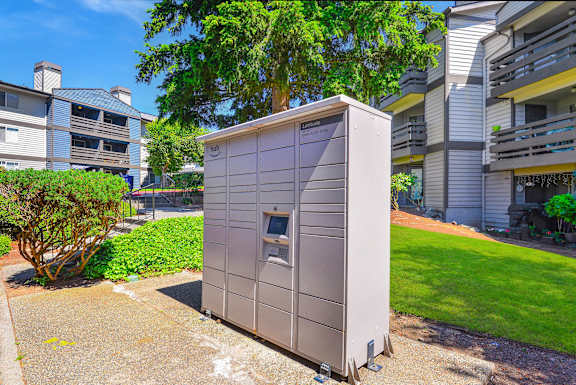 A grey portable toilet is situated on a concrete slab in a grassy area.