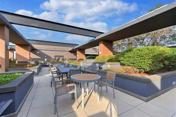 A patio with tables and chairs is covered by a roof.