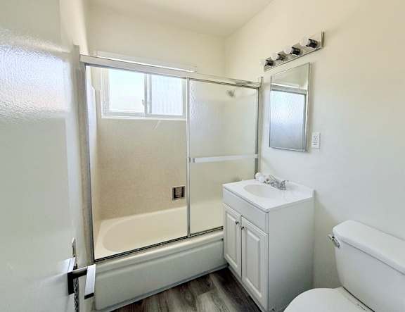 A white bathroom with a toilet, sink, and shower.