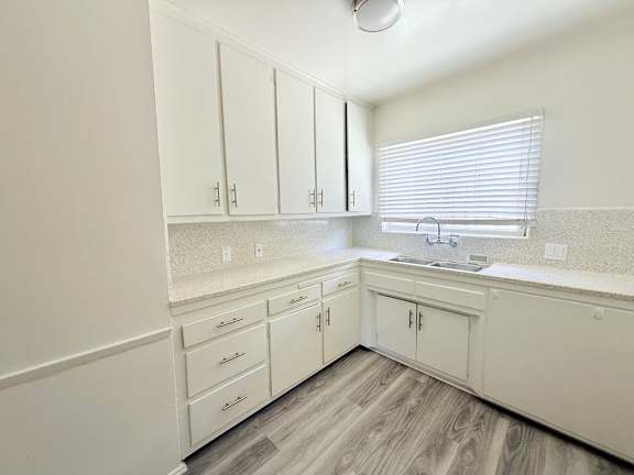A kitchen with white cabinets and a sink.